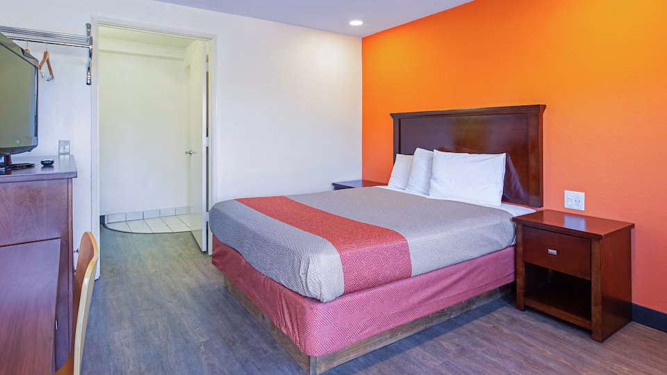 Queen room with colorful bedding, desk, television, and vanity